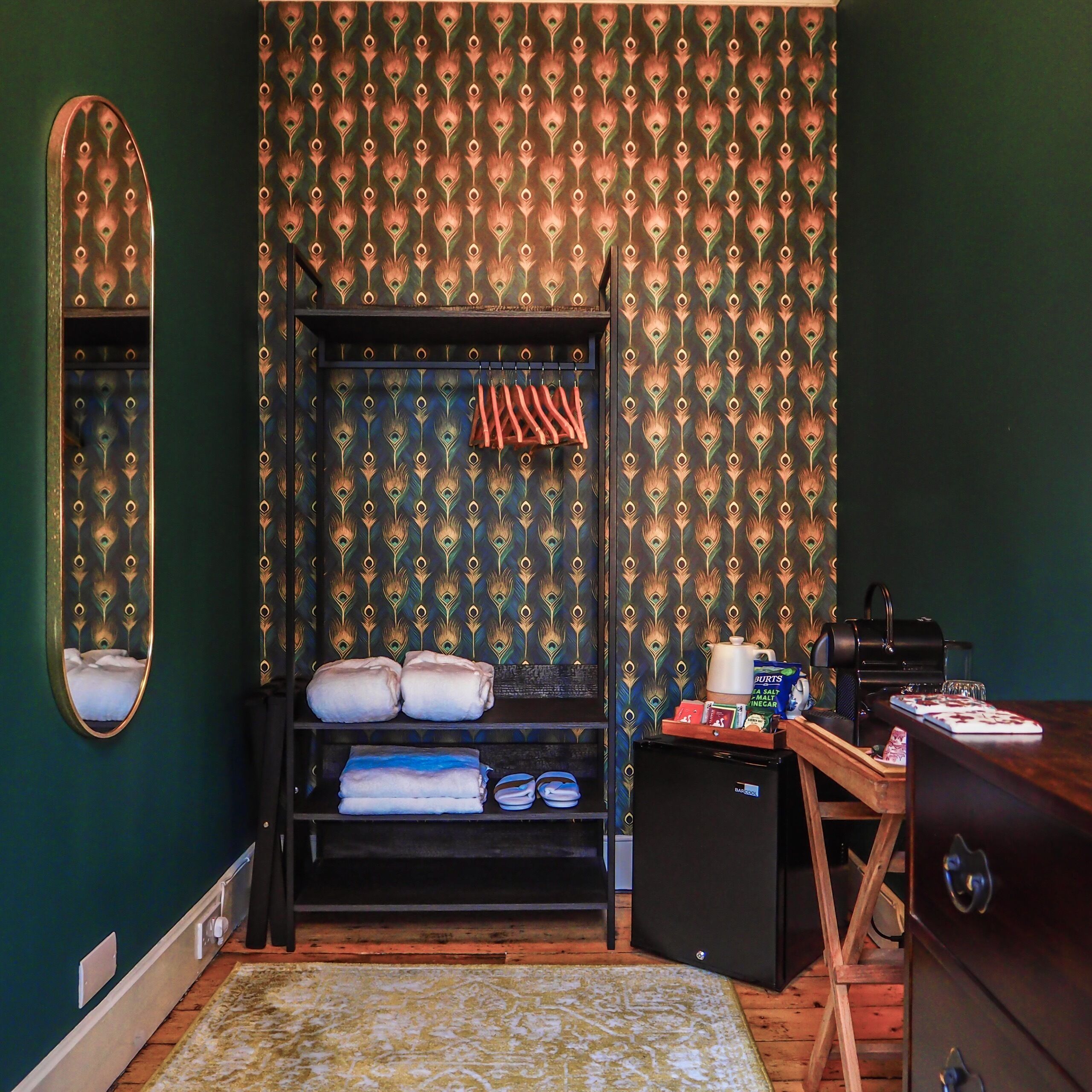 Un dormitorio con cama, cómoda, espejo y una pequeña área de kitchenette.