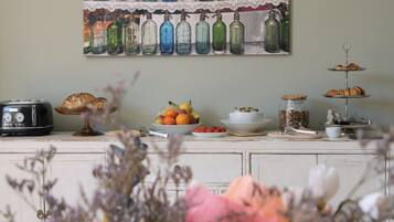 Uma bancada de cozinha com torradeira, pão, frutas e um objeto decorativo na parede.