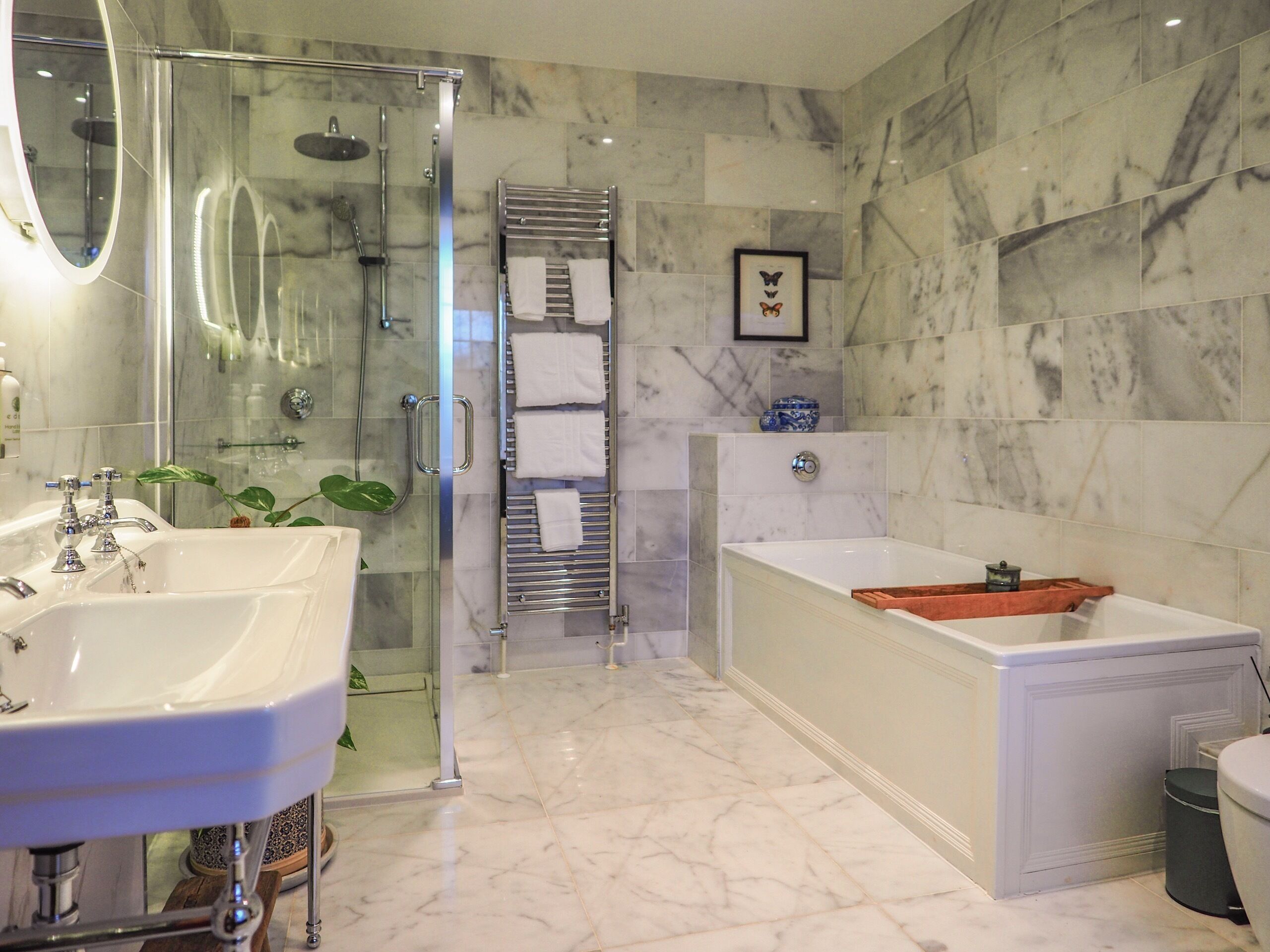 A modern bathroom with a glass shower enclosure, a bathtub, and two sinks.
