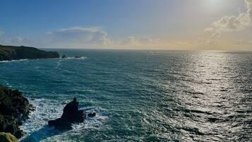 A coastal landscape with a rocky shoreline, waves crashing against the rocks, and a clear sky.