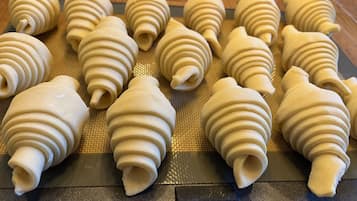 A tray of dough shaped into spirals on a baking mat.