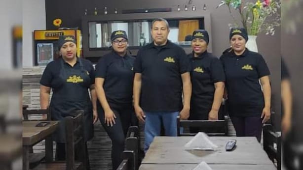 Un gruppo di persone in un ristorante, con un lungo tavolo in primo piano.