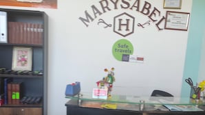 Una reception con un cartello che riporta 'HOSTAL MARYSABEL' e 'Buon viaggio'.