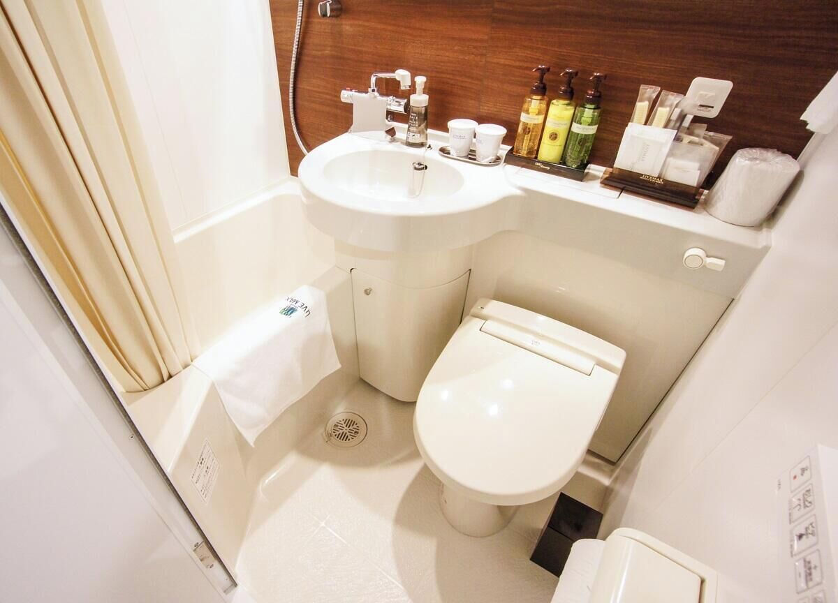 A compact bathroom with a sink, toilet, and a small storage area.