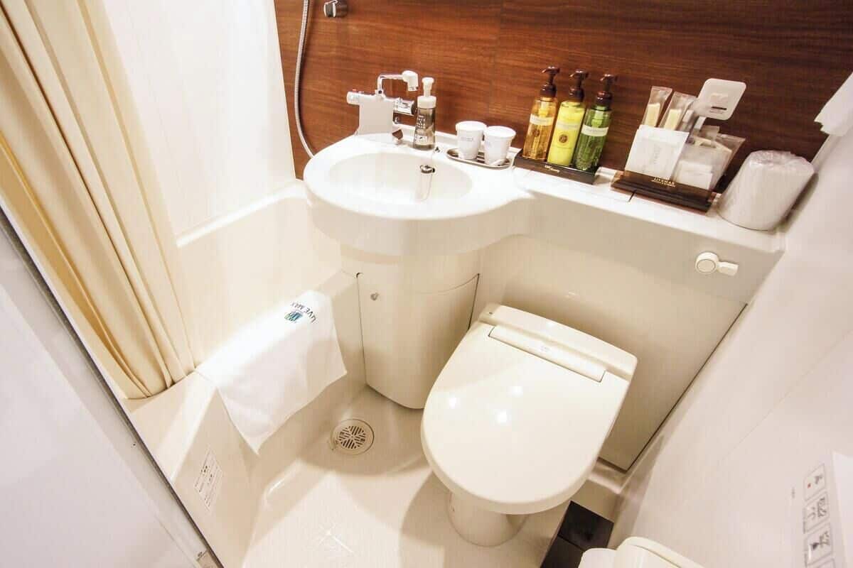 A compact bathroom with a sink, toilet, and a small storage area.