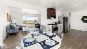 A modern kitchen with a built-in oven, a refrigerator, and a microwave. There is a dining area with a table set for four, and a sofa in the background. - Point Arena Lighthouse - Head Keeper's House (Point Arena)