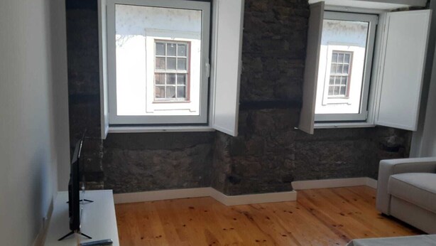 A room with wooden flooring, white walls, and two windows with white frames.