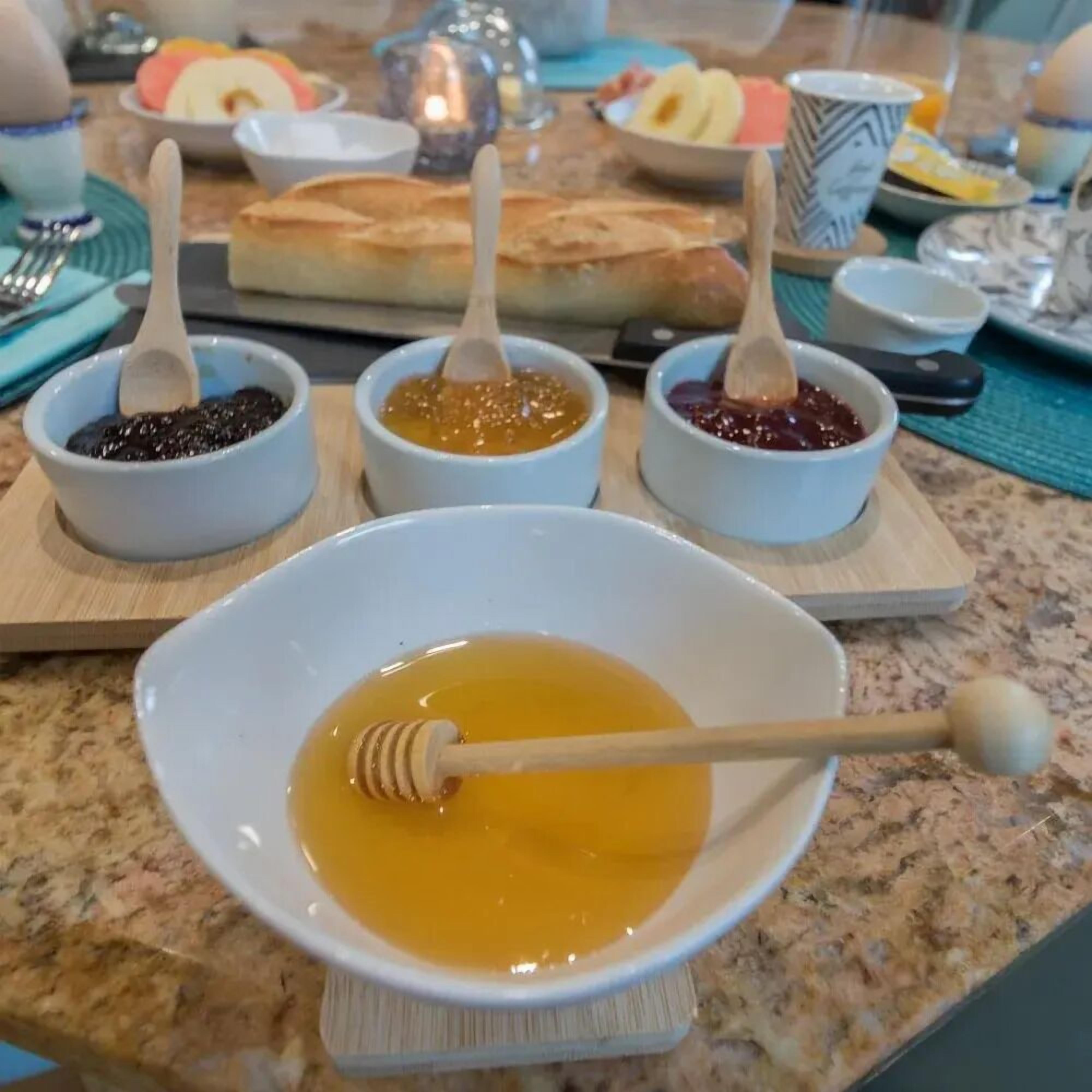 A breakfast table with various condiments and a honey dipper.