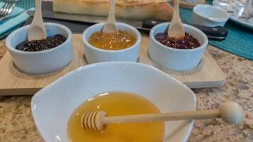 A breakfast table with various condiments and a honey dipper.