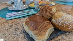Een eettafel met gebak, een koffiezet en een keuken op de achtergrond.