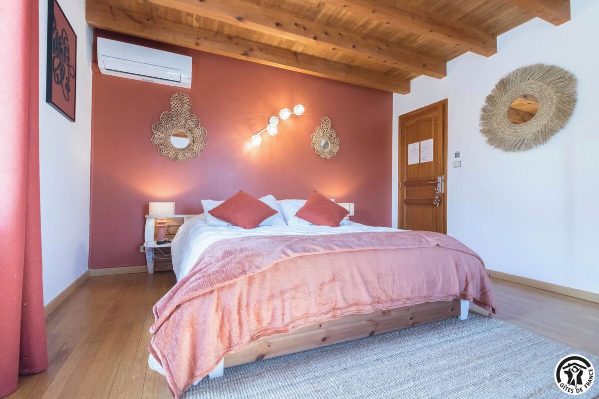 A bedroom with a wooden bed, a nightstand, a wall-mounted light fixture, and a door.