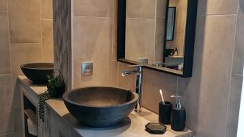 Un baño moderno con un lavamanos de pedestal, un espejo y un perchero para toallas.