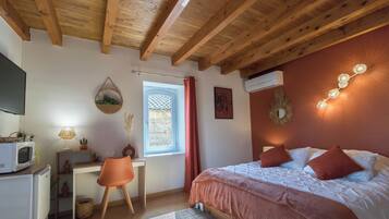 Une chambre à coucher comprenant un lit, un bureau, une chaise, une fenêtre avec un rideau et un climatiseur fixé au mur.