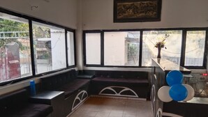 A room with a bench seating area, large windows, and a small table with balloons. - Avexia Fun City Resort  (Mirzapur)