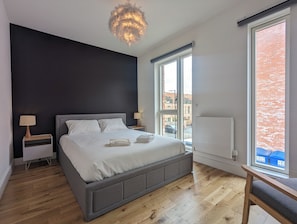 Een moderne slaapkamer met een groot bed, nachtlampjes, een radiator en uitzicht naar buiten.