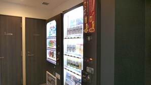 A vending machine with various beverages and snacks, located in a hallway with wooden doors. - HOTEL LiVEMAX Nihonbashi-Ningyocho (Tokyo)