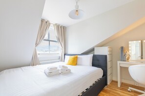 A modern bedroom with a large bed, a bedside desk, and a window with curtains. - 2BDR Hidden Gem in the Heart of Clapham (London)