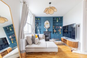 A modern living room with a sofa, a fireplace, a television, and a bookshelf. - 2BDR Hidden Gem in the Heart of Clapham (London)
