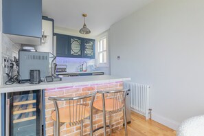 A modern kitchen with a brick accent wall, a built-in bar area, and a window providing natural light. - 2BDR Hidden Gem in the Heart of Clapham (London)