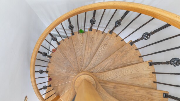 A wooden spiral staircase with metal balusters and a white wall background. - 2BDR Hidden Gem in the Heart of Clapham (London)
