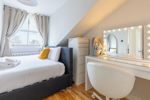 A bedroom with a bed, a vanity with a mirror, and a radiator. - 2BDR Hidden Gem in the Heart of Clapham (London)