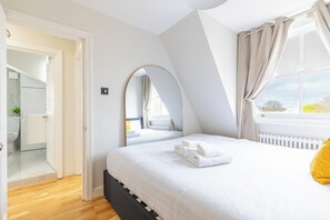 A bedroom with a bed, a window with curtains, a radiator, and a mirror. - 2BDR Hidden Gem in the Heart of Clapham (London)