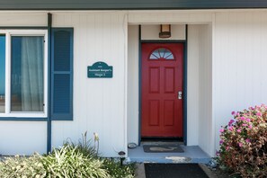 A house with a red door, a sign reading "Assistant Keeper's House 2," and a window with blue shutters.