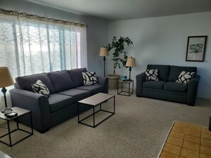 A living room with two sofas, a coffee table, a lamp, a potted plant, and a framed picture on the wall. - Point Arena Lighthouse - Assistant Keeper's House 2 (Point Arena)
