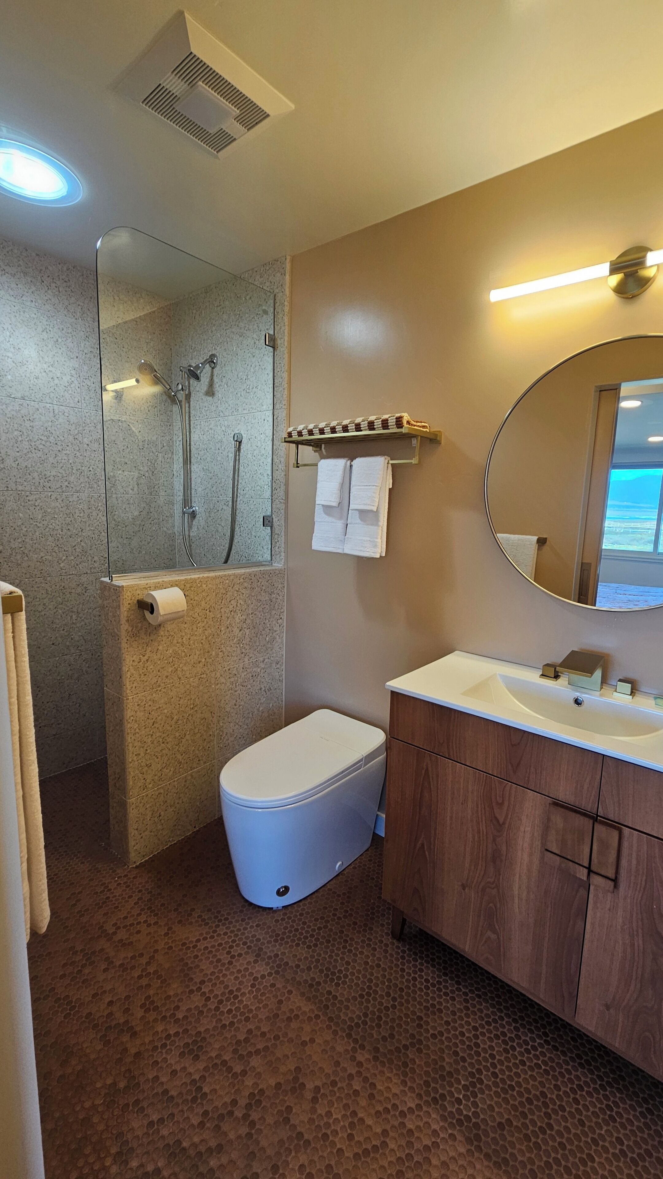 A bathroom with a shower, toilet, sink, and mirror.