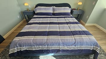 A bed with a striped bedspread, two bedside tables with lamps, and a clock on one of the tables.