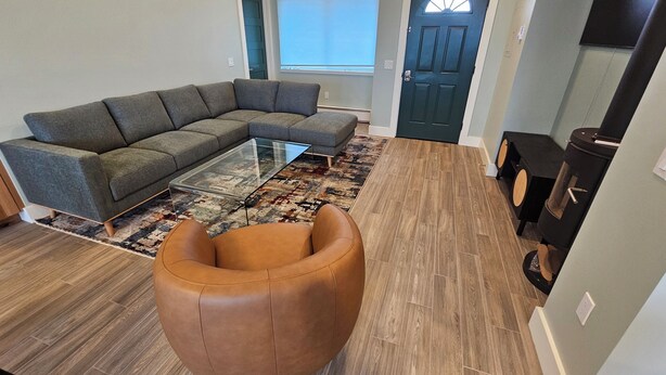 Ein modernes Wohnzimmer mit einem Ecksofa, einem Glastisch und einem braunen Ledersitzhocker.