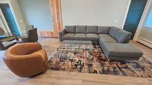 Una sala moderna con un sofá modular, un sillón marrón y una alfombra estampada.