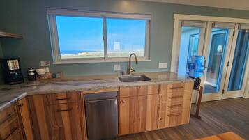 A kitchen with a built-in dishwasher, a sink, and a window overlooking a scenic view.