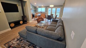 A living room with a sofa, a coffee table, and a fireplace. - Point Arena Lighthouse - Humpback Whale Cottage (Point Arena)