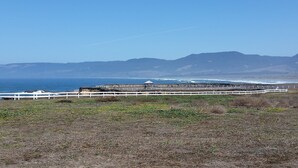 A coastal landscape with a white fence, a gazebo, and a view of the ocean and distant mountains. - Point Arena Lighthouse - Assistant Keeper's House 3 (Point Arena)