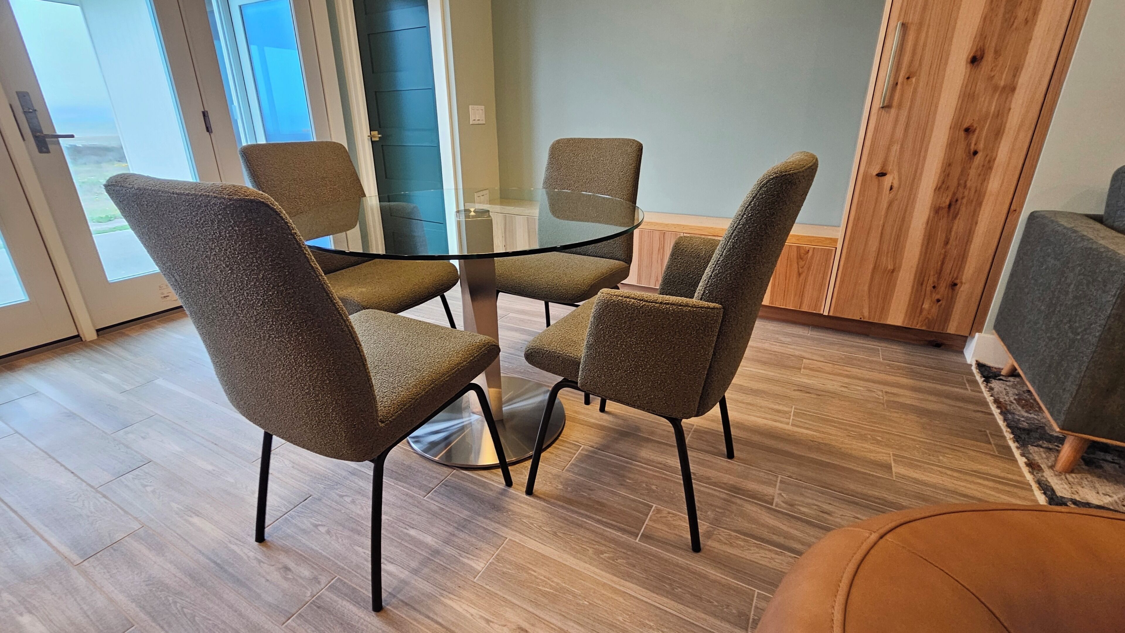 Et moderne spiseområde med et glasbord og fire polstrede stole.