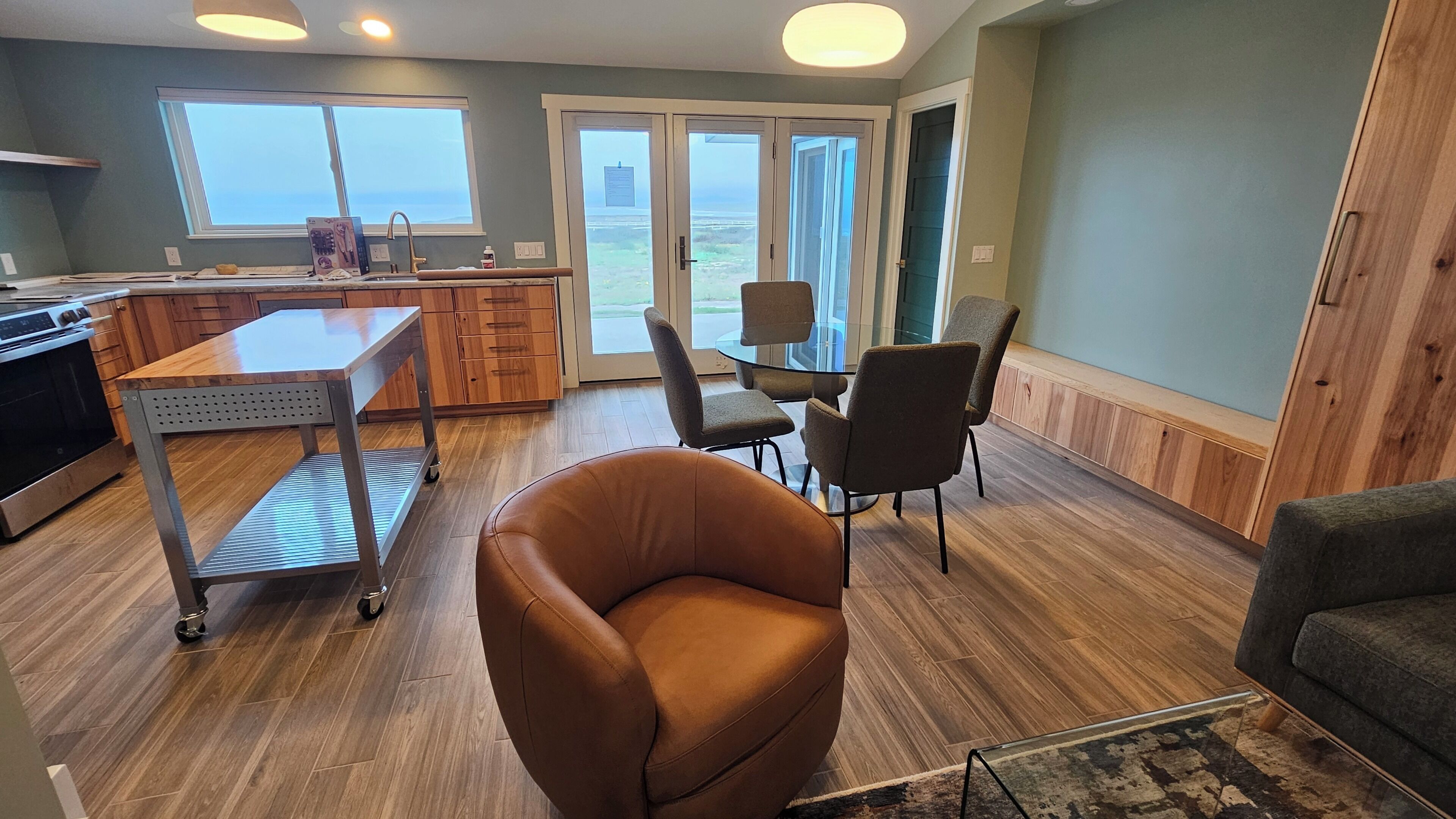 A modern kitchen with a dining area, a large window, and a view of the outdoors.