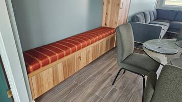 Et værelse med en træbænk, et spisebord med en rund glasplade og en grå sofa.