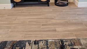 Ein Wohnzimmer mit einem an der Wand befestigten Flachbildfernseher, einem schwarzen Kaminofen und einer schwarzen Unterhaltungsecke mit zwei Lautsprechern.
