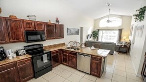 Een keuken met houten kastjes, een magnetron, een fornuis en een spoelbak.