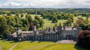 A large, historic building with multiple wings and a central tower, surrounded by expansive green fields and trees. - Renovated farmhouse rural setting,1km from Co Meath village (Oldcastle)