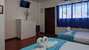 Una camera d'albergo con due letti, una scrivania, una TV e un condizionatore d'aria.