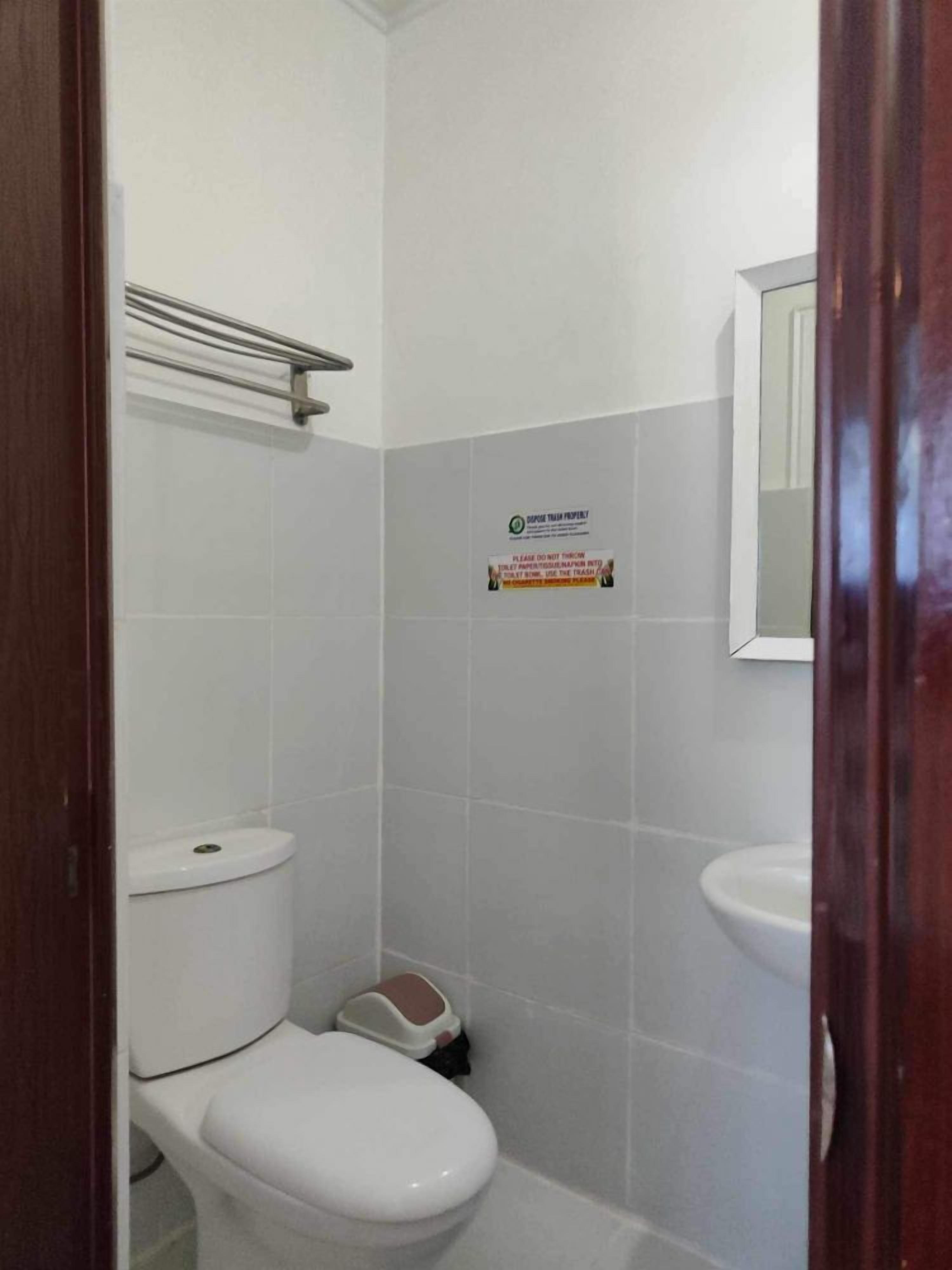 A small, clean bathroom with a toilet, bidet, and a sink. There is a sign on the wall and a mirror above the sink.