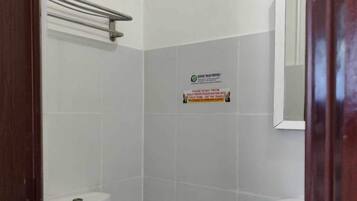 A small, clean bathroom with a toilet, bidet, and a sink. There is a sign on the wall and a mirror above the sink.