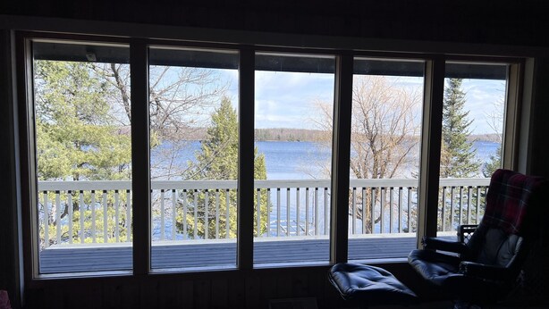 A room with large windows overlooking a lake and a deck.