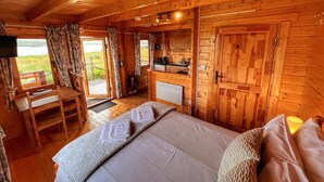 A wooden cabin with a bed, a desk, and a kitchenette. - Harlosh Log Cabins, Cabin No 2 (Dunvegan)