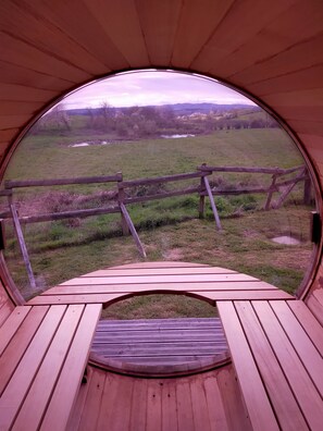 Una estructura circular de madera con vistas a un campo de césped y una valla de madera.