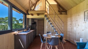 A modern kitchen with a dining area, wooden walls, and a staircase. - Lodge Cèdre Private Spa and Sauna, in a Green Environment, View of the Morvan (BRAZEY EN MORVAN)