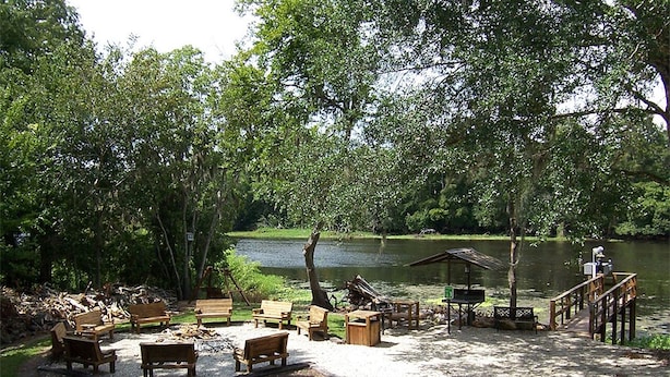 A lakeside park with wooden benches and tables, a dock, and a gazebo. - Riverside Lodge Resort (Inverness)