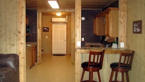 A wooden interior with a kitchen area, a bar stool, and a leather couch. - Riverside Lodge Resort (Inverness)